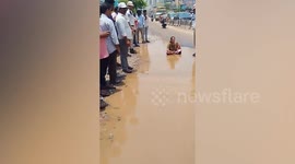 Woman protests over potholes by sitting in dirty puddle
