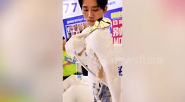 Sales people demonstrate soapy shower dongle by bathing at mall