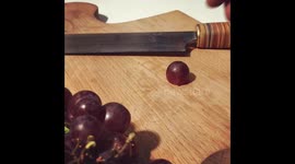 Cutting a grape into small slices with a handmade OOOMS kitchen knife.