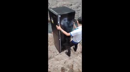 Deliverymen carry fridge through sewer to reach home in Manila slums