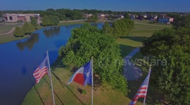 FLAG DAY - Reverse Aerial View of US and Texas State Flags Over A Lake