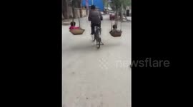 Dad carries two children in baskets while riding a bike