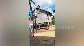 Locals carry wooden house on wheels as they move it down street