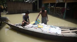 India: A person dry books in a boat near his flooded house