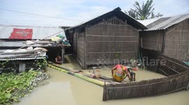 India: A woman is fetching water from a partially submerged hand pump in a flood-affected next to their flooded house