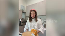 Woman shows off her cake but it falls apart