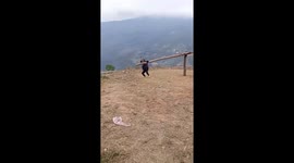Two women play on a giant seesaw on top of a mountain