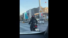 Barbie doll's hair flies high as she rides behind a biker on motorcycle