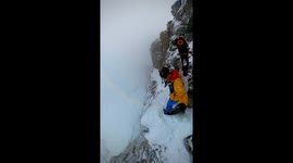 skiers climing along an ice cliff, with a 500 foot drop off