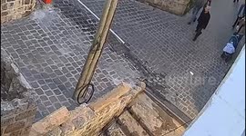 girl on a moped slams into a wall in what looks like a european city