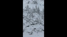 skier on very steep cliff violently smacks a rock on a big drop and tomohawks but is surprisingly ok