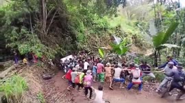Residents of a village of mothers and children in indonesia are busy helping a car that has fallen into a ravine by pulling it with a rope