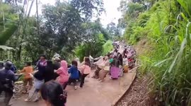 Residents of a village of mothers and children in indonesia are busy helping a car that has fallen into a ravine by pulling it with a rope