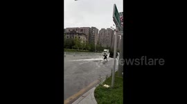 Chinese man surfs behind car on flooded streets during heavy rainfall