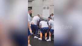 Greek Olympic water polo team get off bus - to lift parked cars out of way
