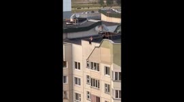 Girl sits on roof edge in Dambroka, Belarus