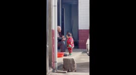 Chinese great-grandfather with trembling hands tenderly feeds great-granddaughter