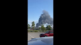 A large, dark plume of smoke rising into the sky, indicating a significant fire in the distance.