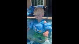 Boy falls asleep in pool while holding umbrella