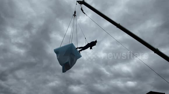 A man preforms a dance routine on a 2.7 tonne block of ice suspended over a Dock in East London