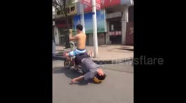 Construction worker sleeps on the back of a moving motorbike