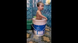 India 's cute little baby is happily swimming in a bucket in the house .