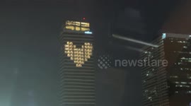 Colleagues illuminate office windows with heart shape