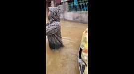 People wade through high floodwaters to receive food supplies when isolated by floodwaters