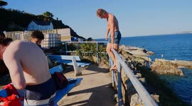 Adult group in unregulated Cliff diving or Tombstoning on the Ocean edge, Cornwall, UK