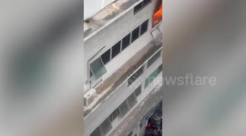 Hero neighbour climbs onto burning building ledge with water hose to help control fire
