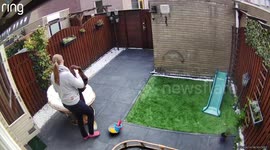 Woman sets up a chair and after she sits down the chair tumbles over and she falls