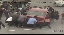 A group of people lift up a car to release a man trapped under it