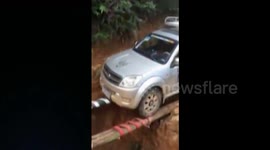 SUV crosses collapsed road on improvised bridge