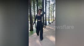 Clumsy young woman falls into slimy green pond during fashion shoot in designer clothes