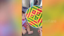 Cute toddler grins and blows air while smiling as mum waves fan to his face