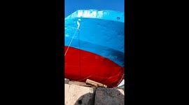 Painter writes Chinese characters on the side of cargo ship