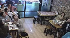 Monitor lizard smashes through hole in restaurant ceiling above shocked diners