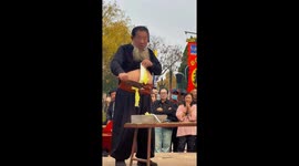 Street performer chops vegetables with a knife on his stomach in Hebei, China