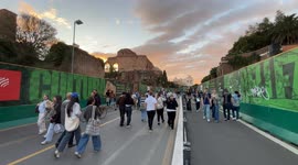 Tourists stroll along Via dei Fori Imperiali at sunset on a peaceful October Sunday in Rome.