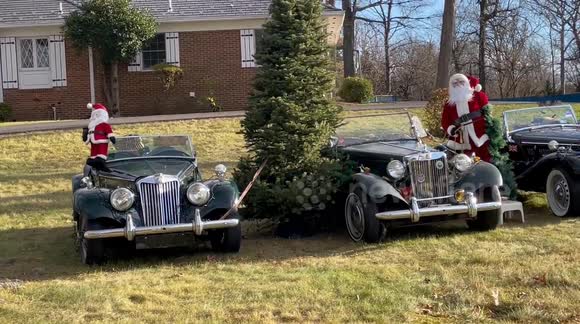 Santas with three British antique cars and other Christmas decorations in Potomac, Maryland USA
