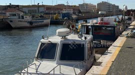 A small motorboat with two people on board goes up the canal port with the moored fishing boats and passes under the Ponte 2 Giugno, the mobile bridge connecting it to the Isola Sacra area of ​​Fiumicino.