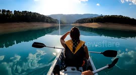 Kayak rowing slow motion. Kayaker woman and man kayaking in beautiful landscape at Embalse de la Bolera, Spain. Kayakers practice sports in a kayak at the lake. Aquatic sports during summer
