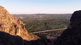 Sportsman crosses suspended bridge at canyon silhouette of man doing a via ferrata in Redovan, Alicante, Spain.