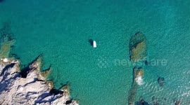 Yacht relaxation on crystal clear turquoise water at beach in the south of Spain, in Murcia. Aerial drone shot of two women taking a bath near a boat.