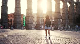 Aqueduct of Segovia visited by girl travelling to Spain walking arround this artichetectural structure which is considered as a world heritage.