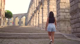 Aqueduct of Segovia visited by girl travelling to Spain walking arround this artichetectural structure which is considered as a world heritage.