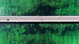 Top overhead aerial view of motorway or road bridge amidst ocean or mediterranean sea.
