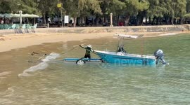 A Toyota pickup truck struggles to tow a boat from the ocean, the tires kept skidding and getting stuck in the sand.