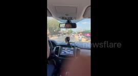 Persistent vendors stand on road to invite passing drivers to their food stalls