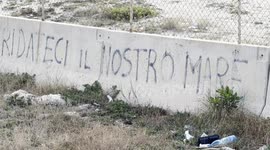 The writing 'give us back our sea' appears on one of the blocks that delimit the area where Royal Caribbean plans to build the first large privately managed tourist port in Italy and in the background the old lighthouse of Fiumicino, near Rome.